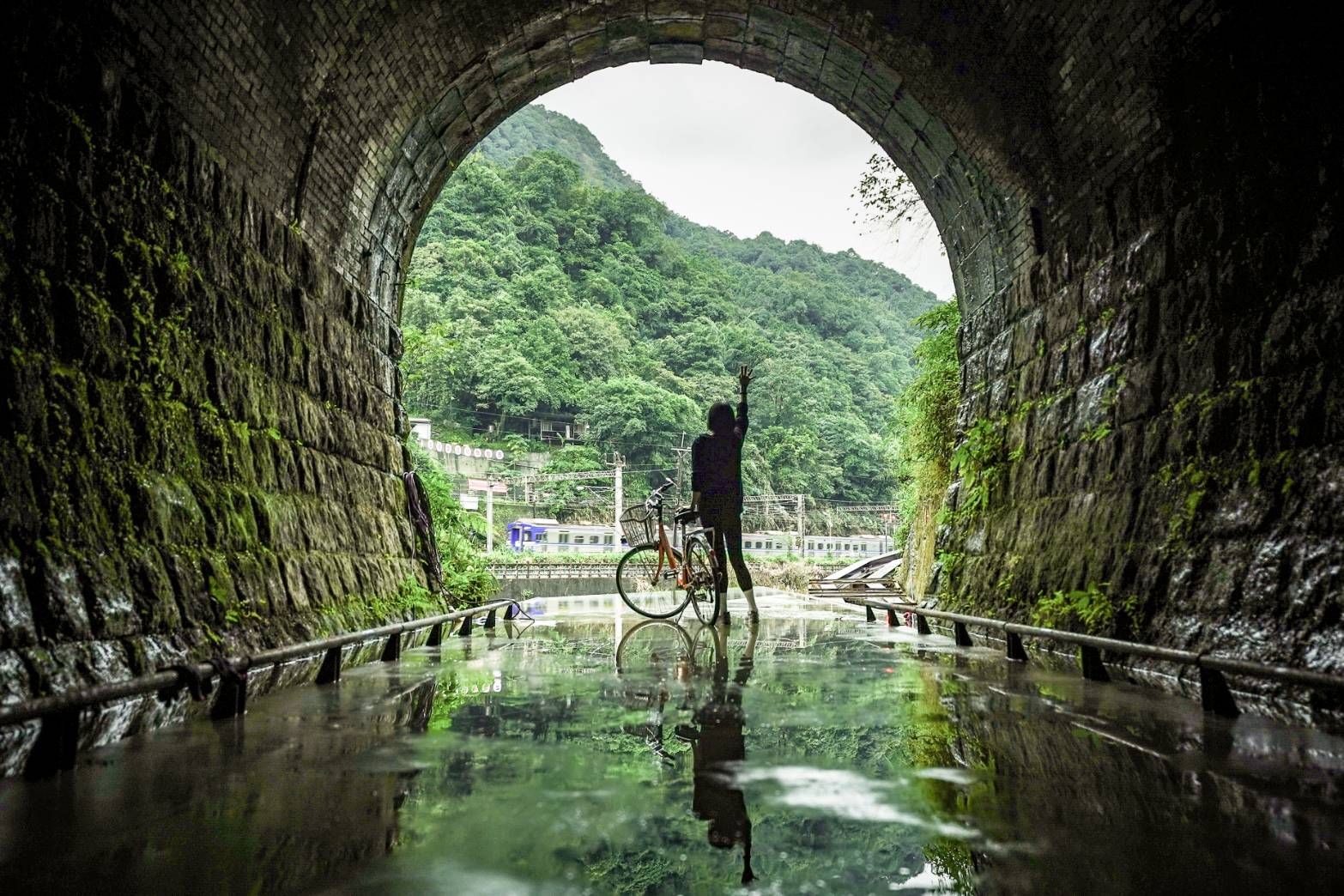 即將於7月試營運的三貂嶺自行車道三瓜子隧道西口的水池鏡面，一片水鏡不僅將日光引入黑暗的隧道，也映射環繞的天空與隧道外壯闊山景，連不時經過的火車也偶然也可拉近眼前