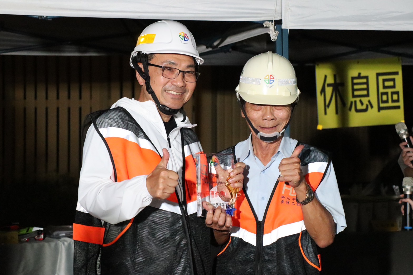 侯友宜市長（左）20日深夜視察新北大道夜間鋪路情形，並頒發獎牌感謝李永川顧問（右），也是淡江大橋混凝土配比設計的李顧問，多年來協助市府提升道路品質、輔導管控瀝青品質的貢獻。