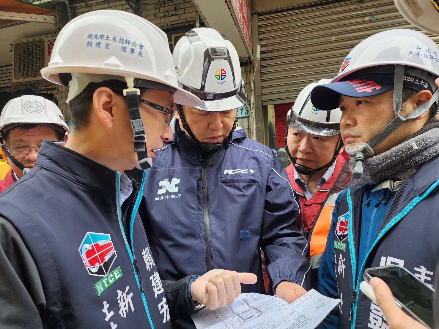 圖說： 新北市副市長朱惕之(中)關心三重區六張街工地損鄰案，到現場聽取工務局長馮兆麟(右2)及新北土木技師公會賴建宏理事長(左2)說明損鄰肇事原因及處理方式。