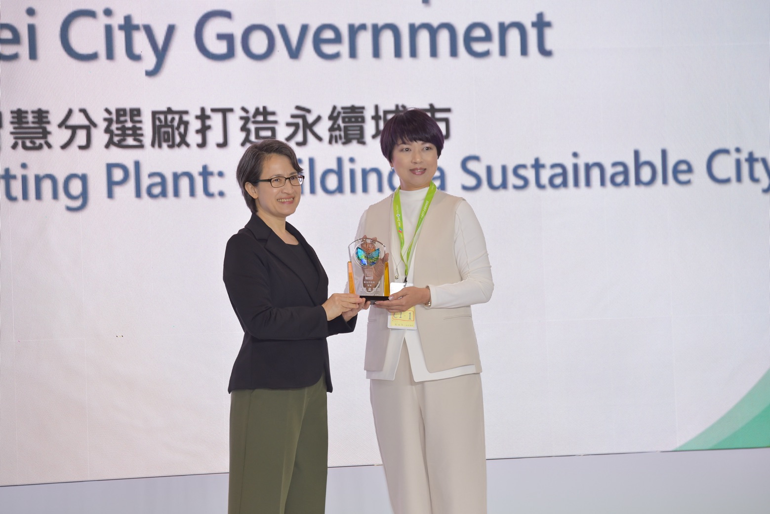 新北市政府「建築執照AI輔助審查」及「AI智慧分選廠打造永續城市」，榮獲智慧城市創新應用獎，副總統蕭美琴（左）頒發表揚，新北市政府副秘書長龔雅雯（右）代表市府團隊領獎。
