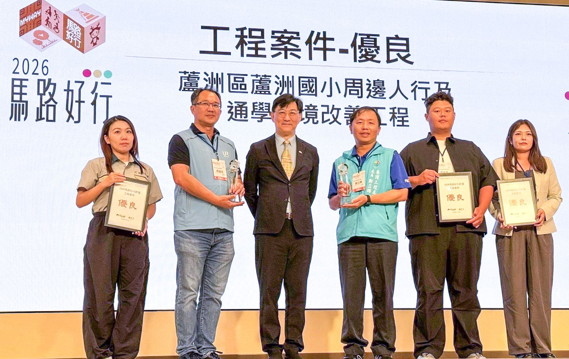 蘆洲國小周邊人行及通學環境改善工程,在2026馬路好行評選獲得優良,養工處長鄭立輝(左四)出席典禮接受頒獎。