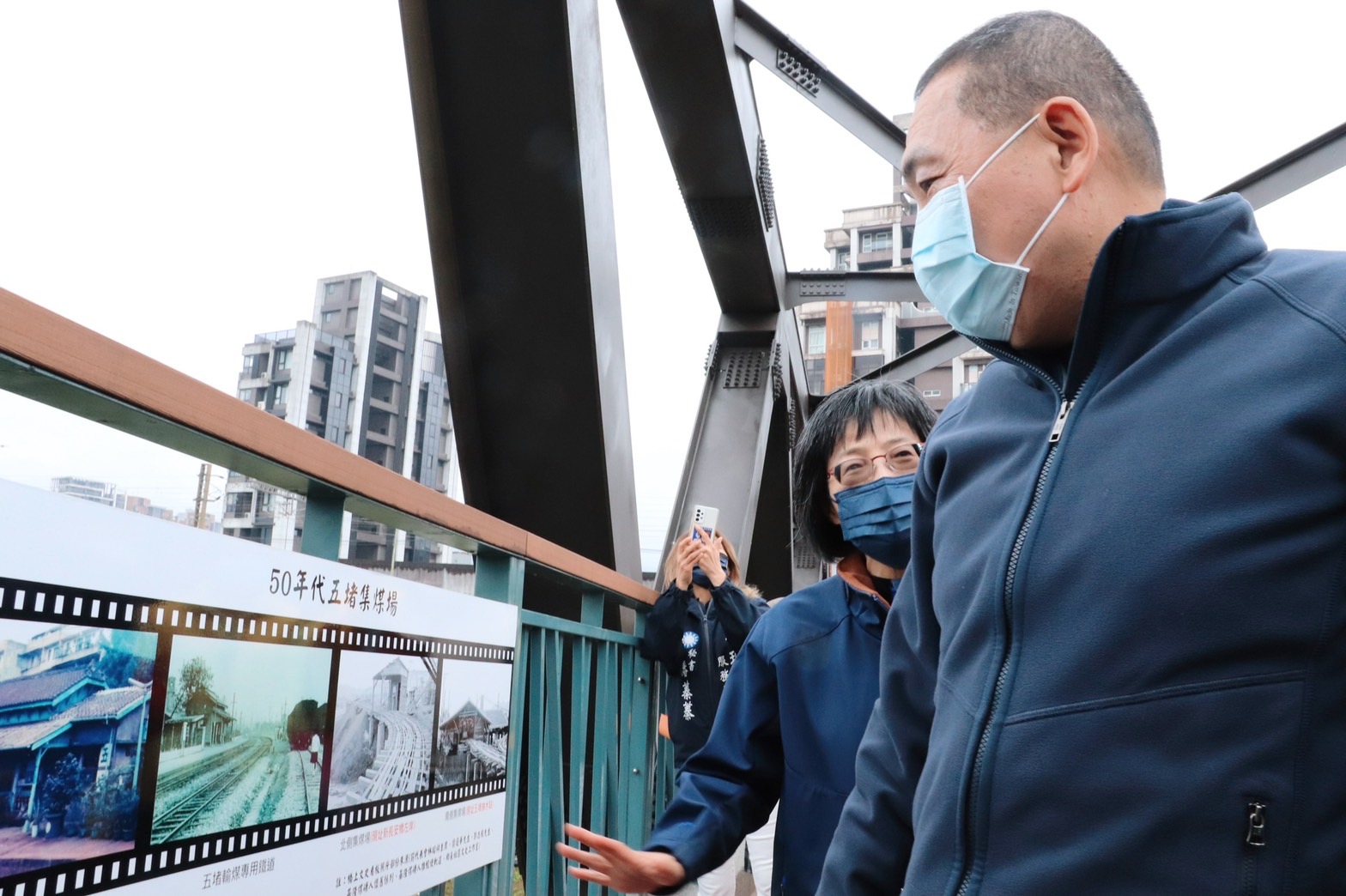工務局長祝惠美（左）向侯友宜市長（右）介紹橋上設有汐止地區的文史相片，讓民眾了解在地歷史人文。